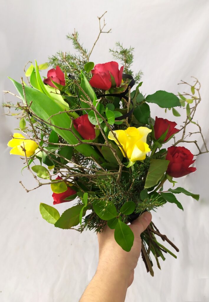 smuteční kytice na položení s červenými a žlutými růžemi a tulipány, střapatá s větvičkami